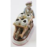 Continental porcelain of a boy pushing a barrow of broken large eggs.