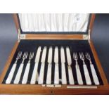 A silver set of fruit knives and forks with mother of pearl handles, within walnut fitted box, by