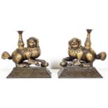 A pair of gilt copper fu lions on stands bearing vasiform incense holders on backs, 19th/20th