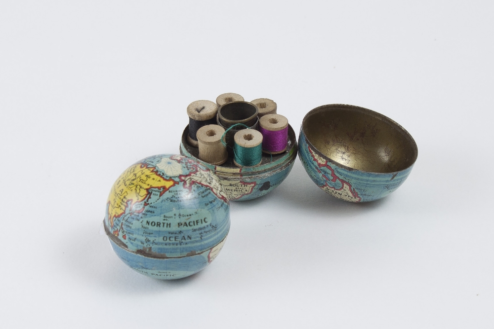 Two small enameled metal earth globes which hold 6 thread reels and 1 thimble. Diameter: 4,3 cm.
