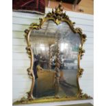 NV- A large decorative wall mirror with a gilt work frame of foliate and scroll work decoration