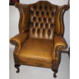 NV- An old gold coloured buttoned leather wing-back armchair