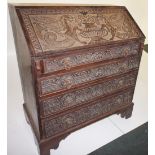 NV- A heavily carved oak bureau with a fall front with griffin decoration, enclosing a fitted