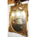 NV- A large decorative wall mirror with a gilt work frame of foliate, ribbon and scroll work