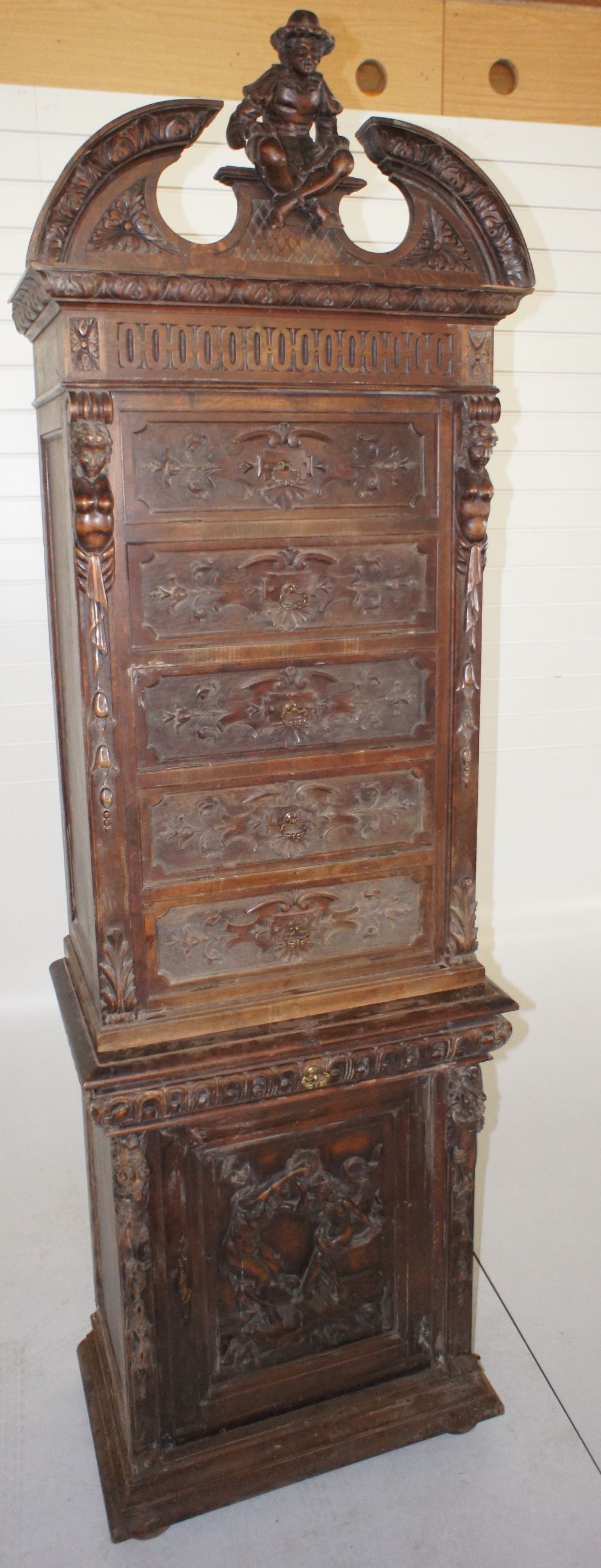 NV- A heavily carved oak cabinet with fall front upper drawers and a cupboard below