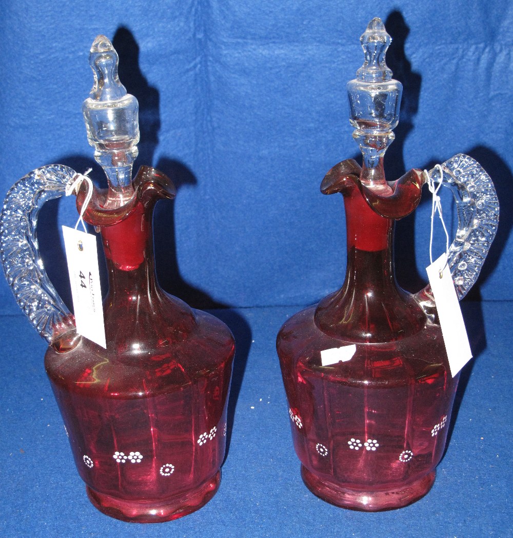 Pair of late 19th century cranberry glass mallet shaped ewers with blown clear stoppers and