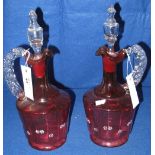Pair of late 19th century cranberry glass mallet shaped ewers with blown clear stoppers and