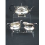 GEORGE V SILVER THREE PIECE OVAL TEA SET raised on bun feet comprising tea pot, cream jug and two