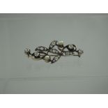 A VICTORIAN DIAMOND AND PEARL SET BROOCH.  The naturalistic design depicting scrolling leaves and