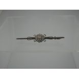 AN EDWARDIAN DIAMOND BAR BROOCH.  The central diamond flowerhead cluster milligrain set with