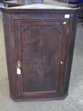 LATE GEORGIAN OAK HANGING CORNER CUPBOARD having moulded cornice over cross banded panelled door