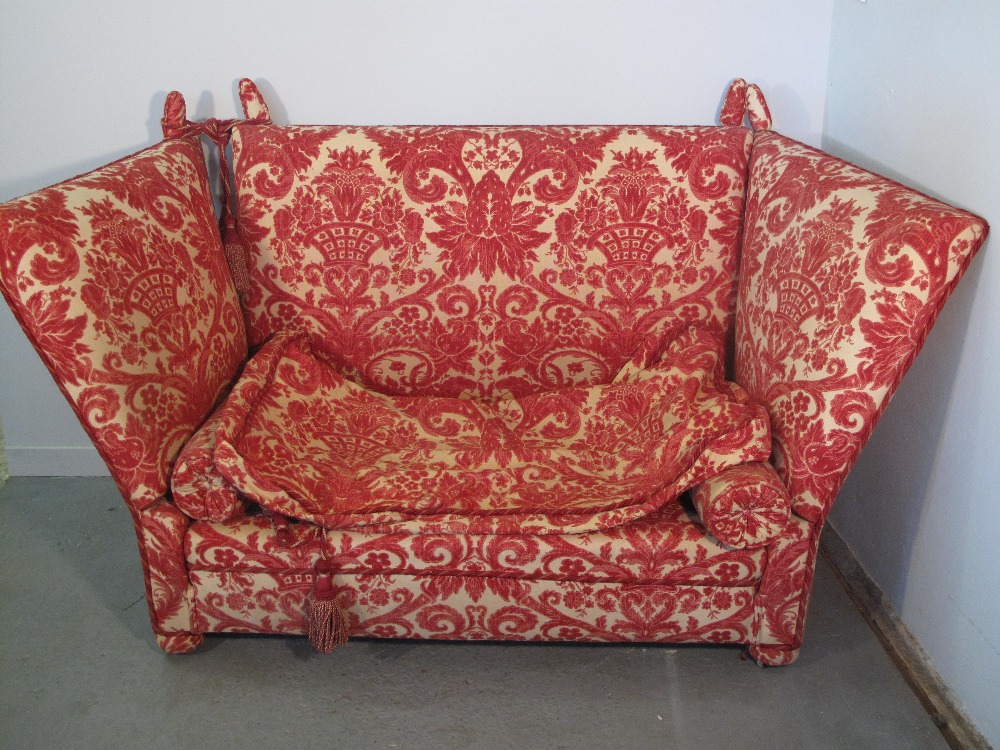 A Knole type drop ended high backed sofa with printed foliate design upholstery and bolster