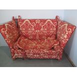 A Knole type drop ended high backed sofa with printed foliate design upholstery and bolster