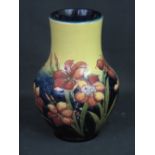 MOORCROFT POTTERY BALUSTER VASE decorated with tube lined stylised flowers on a two tone ground.