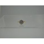 AN 18CT GOLD AND DIAMOND DAISY CLUSTER RING.  The central old cut diamond an estimated 0.35cts