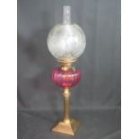 VICTORIAN BRASS AND CRANBERRY DOUBLE GLASS  OIL LAMP, with etched foliate glass globular shade on