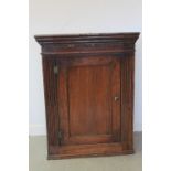 GEORGE III OAK HANGING CORNER CUPBOARD having moulded and dentil cornice over single blind