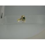 AN 18CT GOLD EMERALD AND DIAMOND CLUSTER RING.  The central oval emerald measuring 8mm x 6mm and