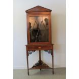 EDWARDIAN MAHAGONY INLAID CORNER CABINET ON STAND having architectural pediment over cross-banded