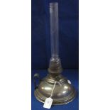 White metal chamber type oil lamp with loop handle and clear chimney.