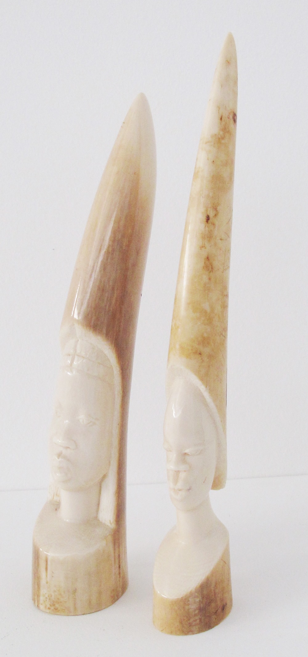 Two Tribal African carved ivory elephant tusks depicting faces. Early 20th century. L25cm and L23cm.