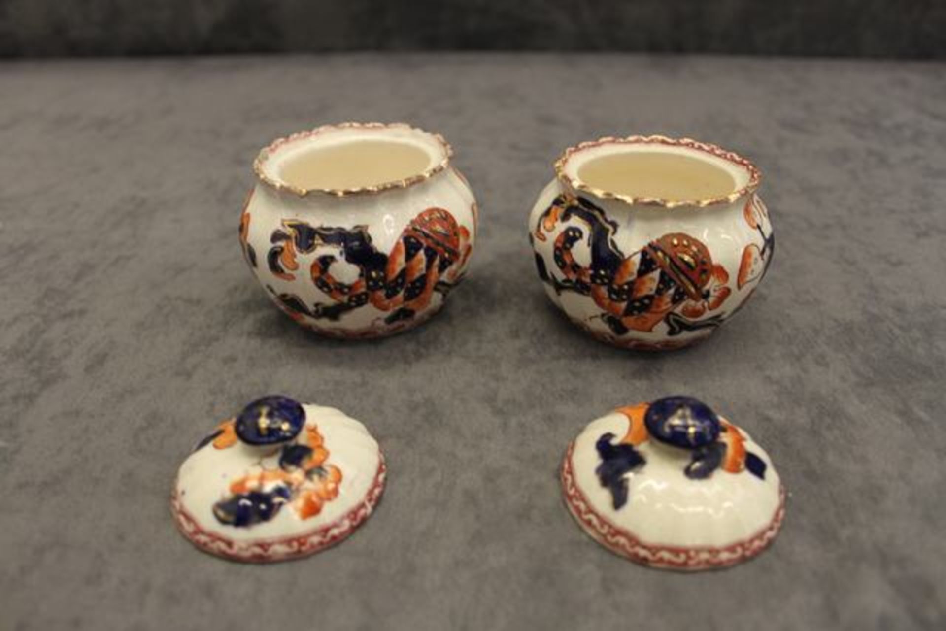 A pair of Royal Doulton lidded pots, decorated in cobalt blue & burnt orange with gilt highlighting,