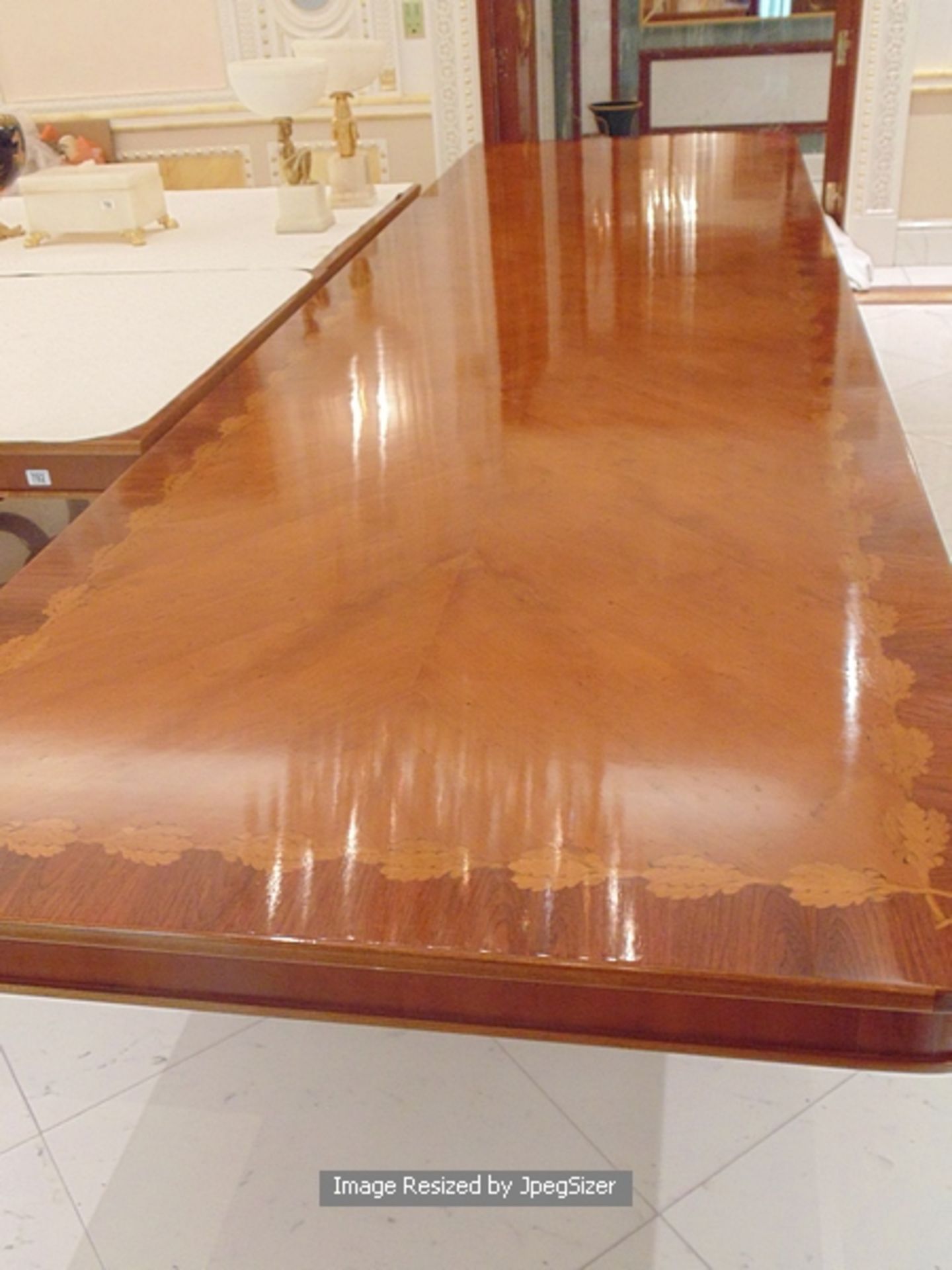 A Regency style mahogany and rosewood banded dining table, the mirror veneered top enclosed by