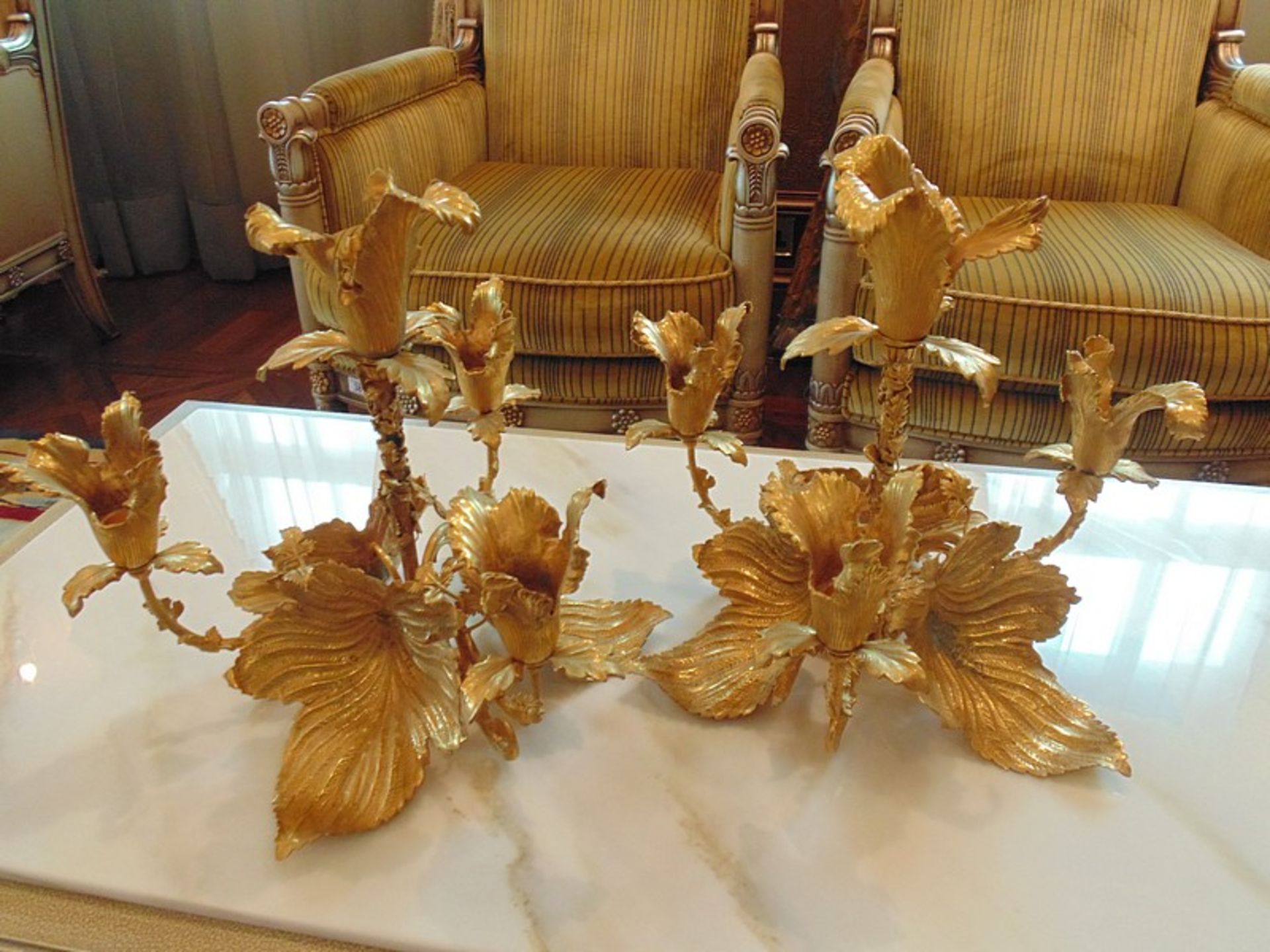 A pair of bronze with applied 24ct. gold leaf four branch candelabras in the form of a flower