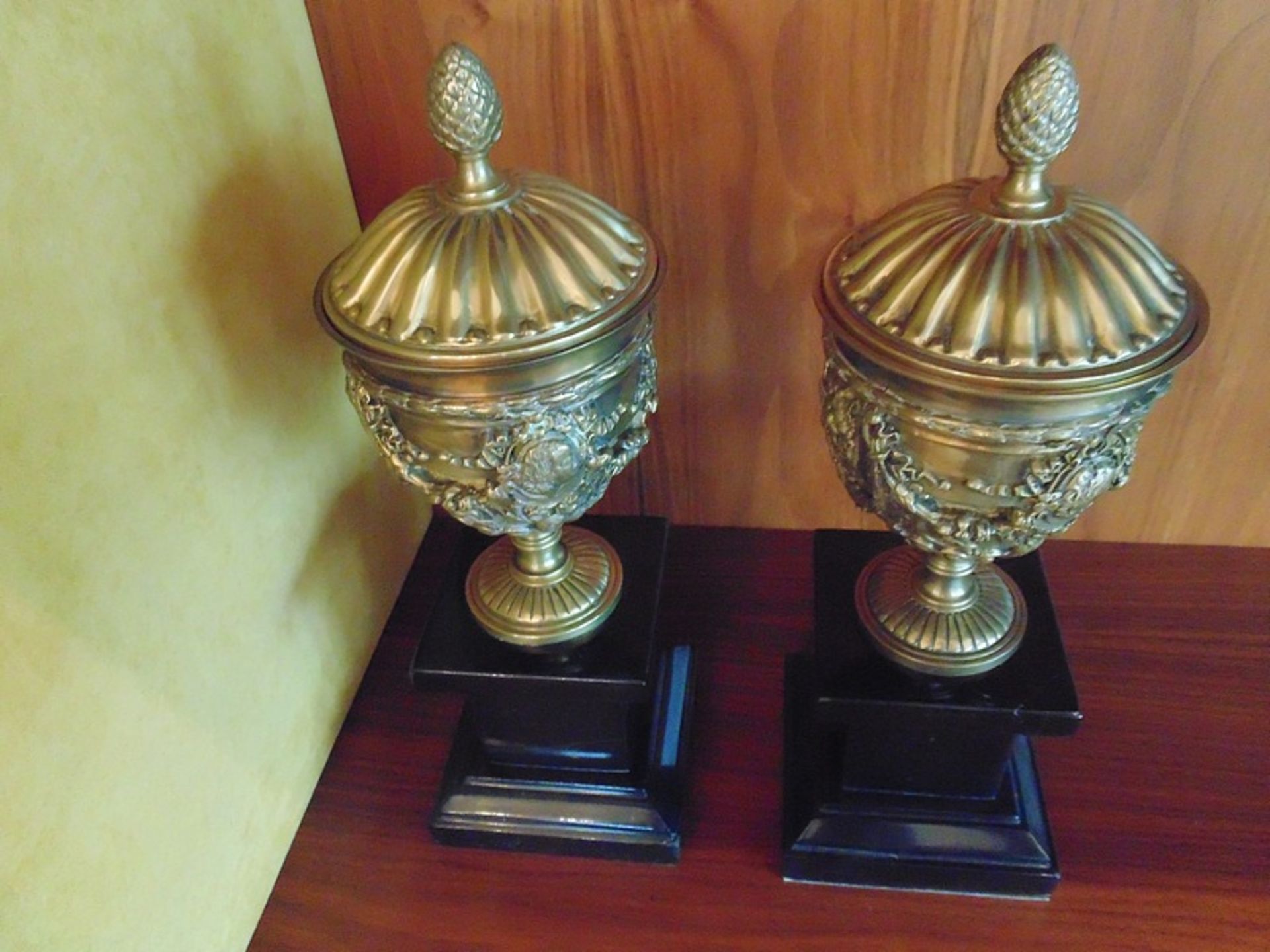 A pair of Italian Neoclassical gilt bronze urns cast in relief mounted on a black marble plinth