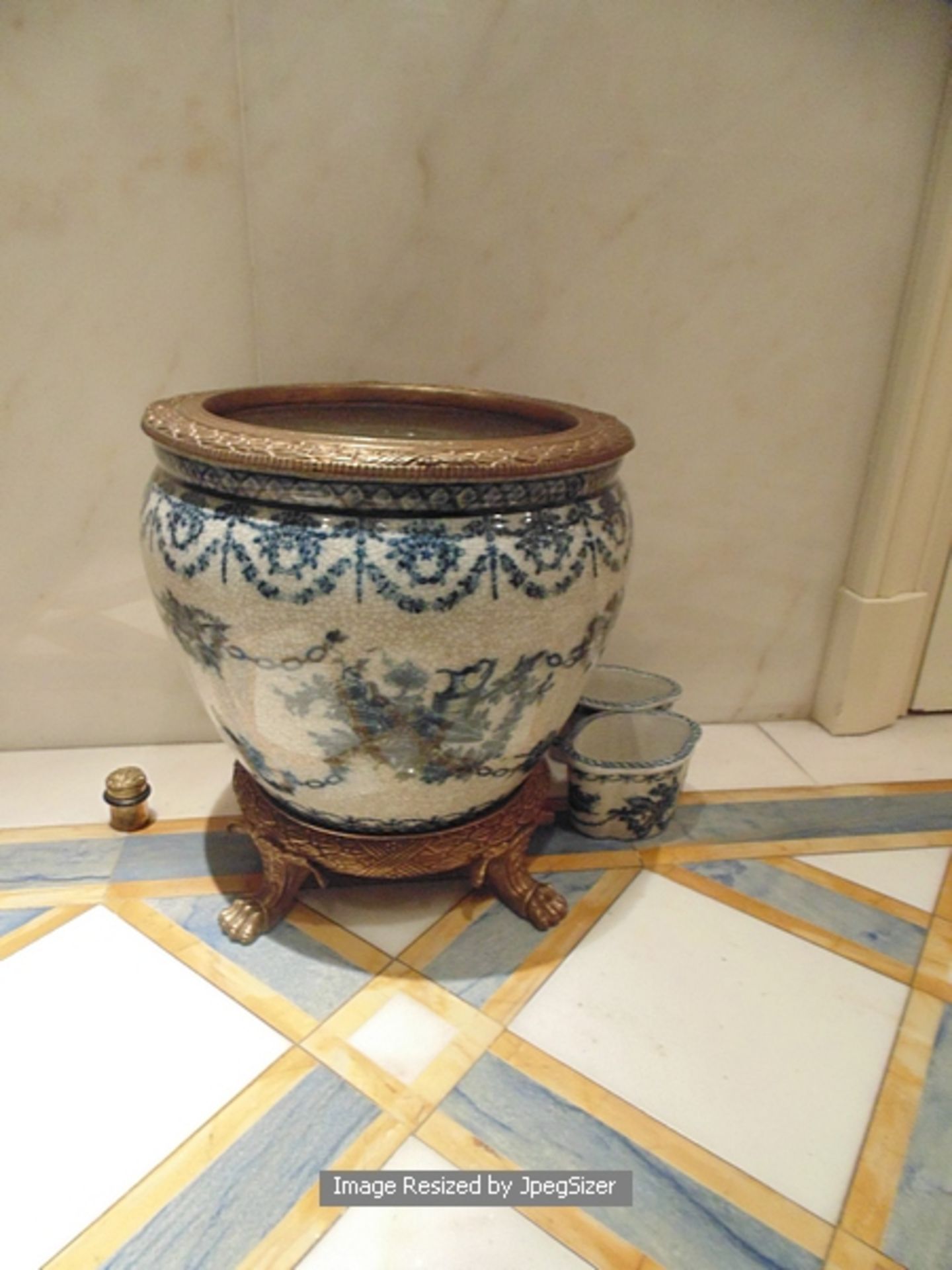 A blue and white crackleware ceramic waste paper bin with a bronze decorated top rim mounted on a