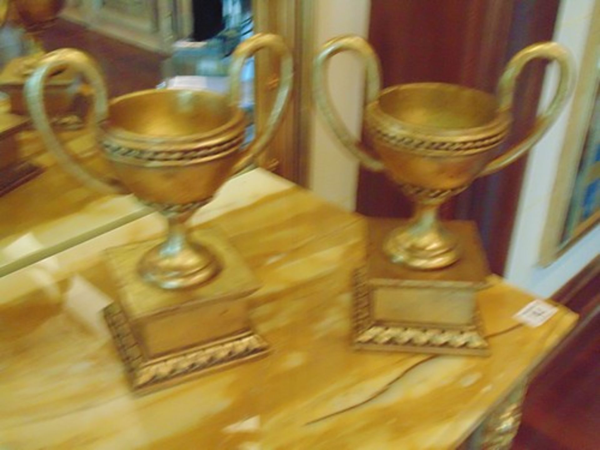 A pair of faux Empire style trophy cups with handles on base  light wooden twin handled faux