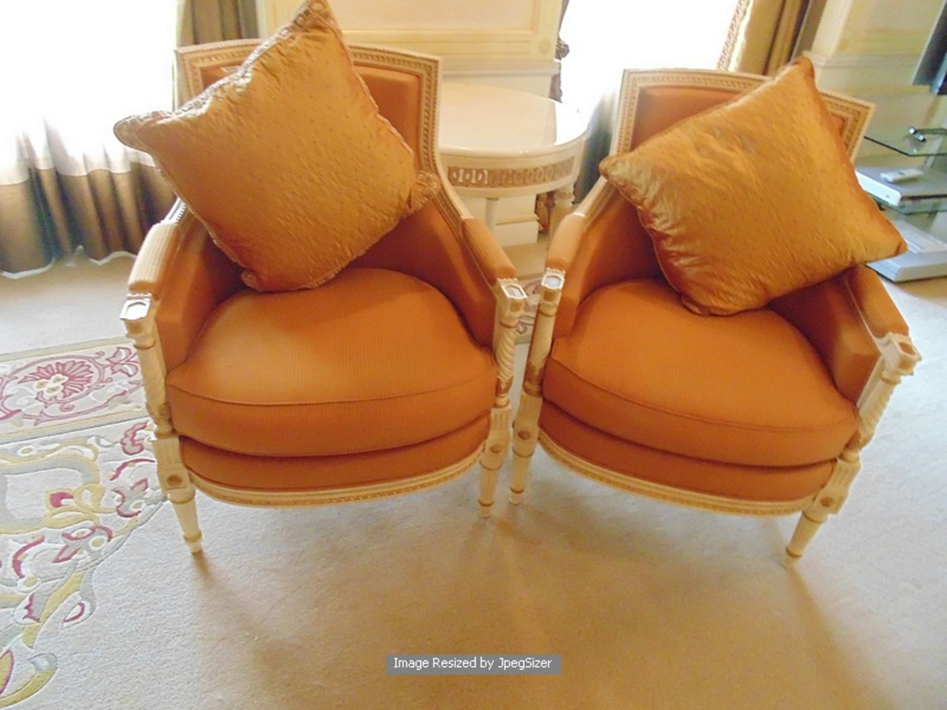 A pair of Louis XVI style white painted armchairs, the carved wooden frames detailed throughout with