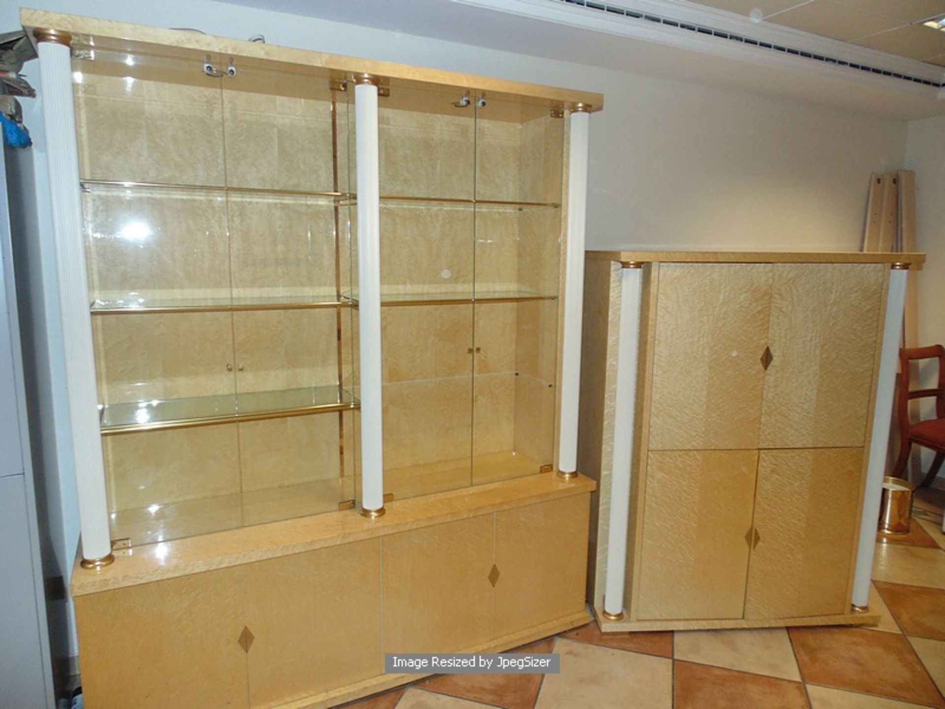 A birds eye maple display cabinet with glass shelves enclosed by four glass doors, fitted with