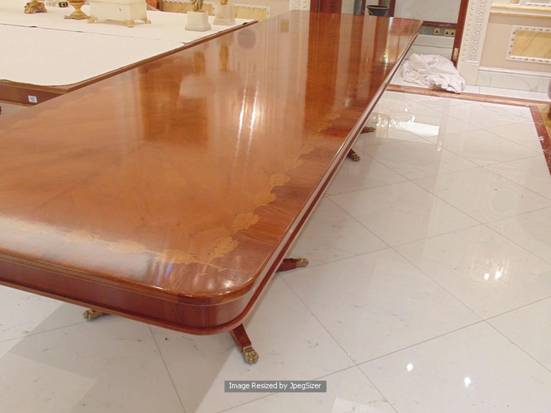 A Regency style mahogany and rosewood banded dining table, the mirror veneered top enclosed by