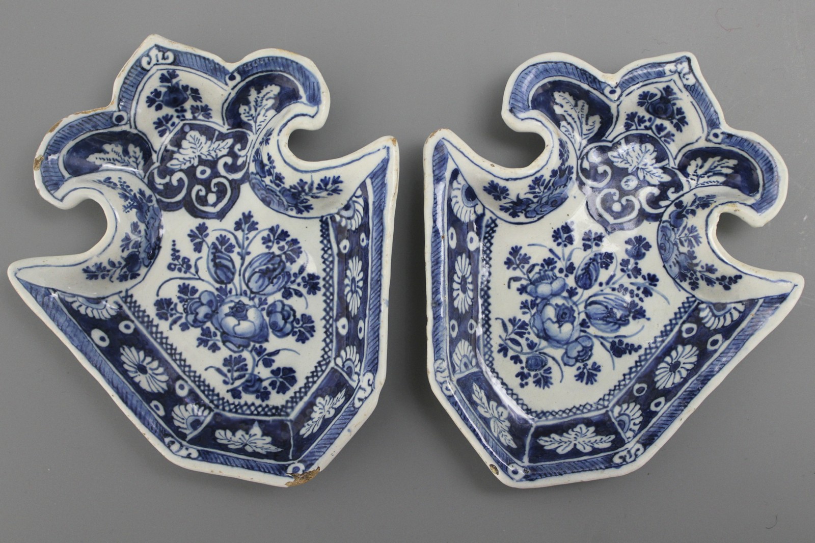A pair of fleur-de-lys shaped Dutch Delft condiment plates, ca. 1700 Decorated with floral sprigs