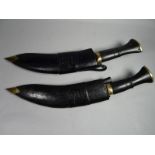 A pair of military-style Nepalese kukries in black leather and brass-tipped scabbards