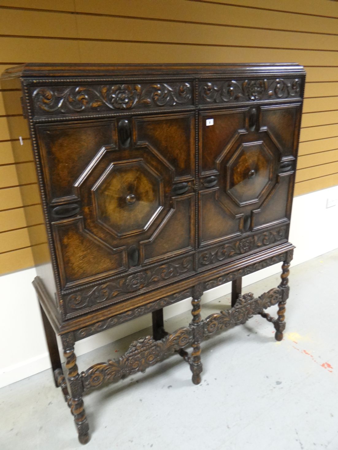 An early-twentieth century carved and stained raised cabinet with geometric panelling with floral