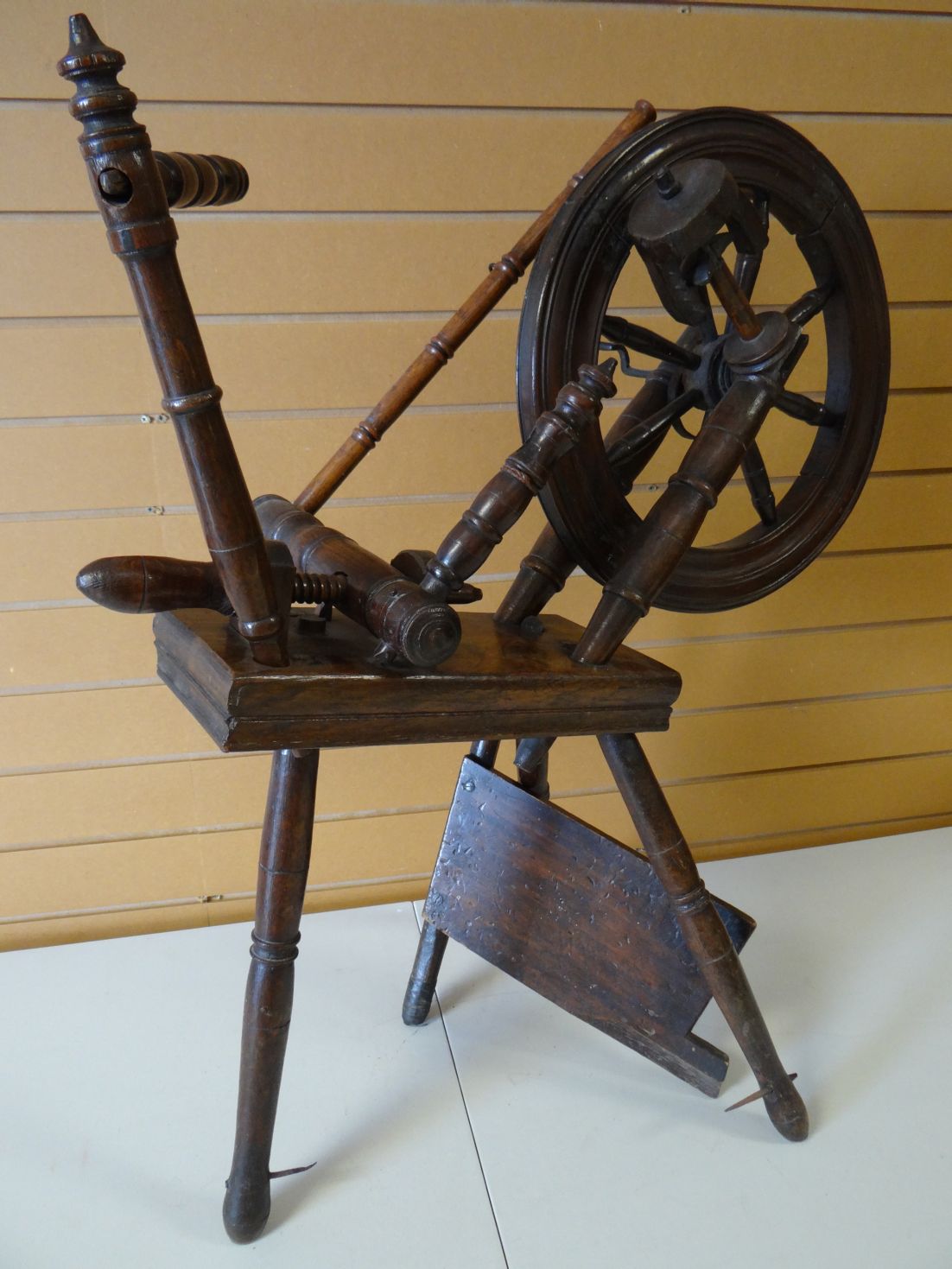 An early nineteenth century Welsh oak spinning wheel on three pointed and turned feet, wheel