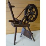 An early nineteenth century Welsh oak spinning wheel on three pointed and turned feet, wheel