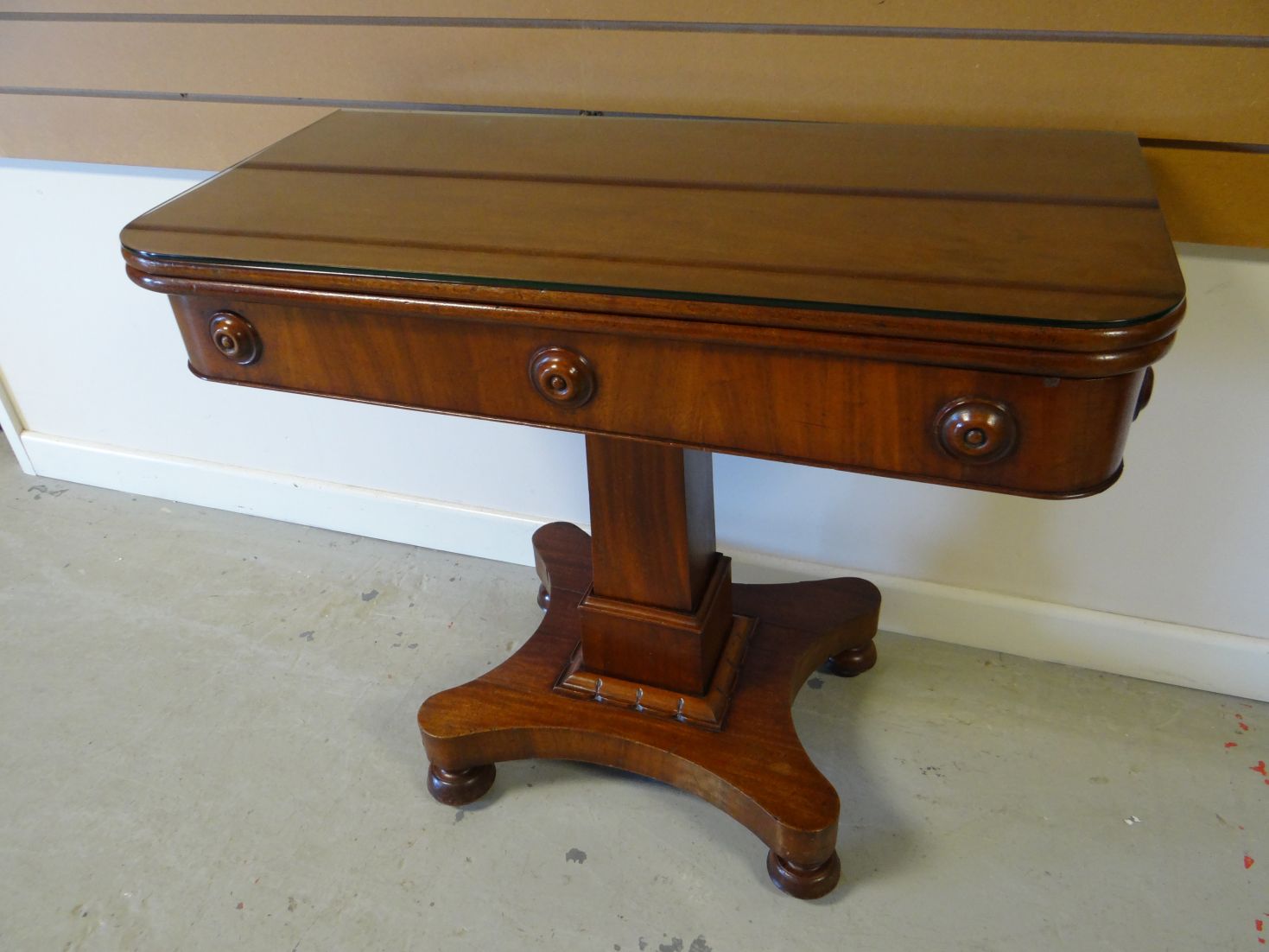 A mahogany fold-over tea-table with column support on a shaped base, 35.5 ins wide (90 cms)