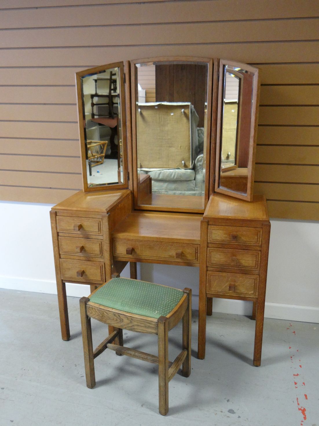 A light oak Brynmawr Furniture pedestal dressing-table with bank of seven panelled drawers and tri-