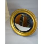A circular gilt framed convex mirror with ebonised slip and laurel border, 20 ins diam (51cms)