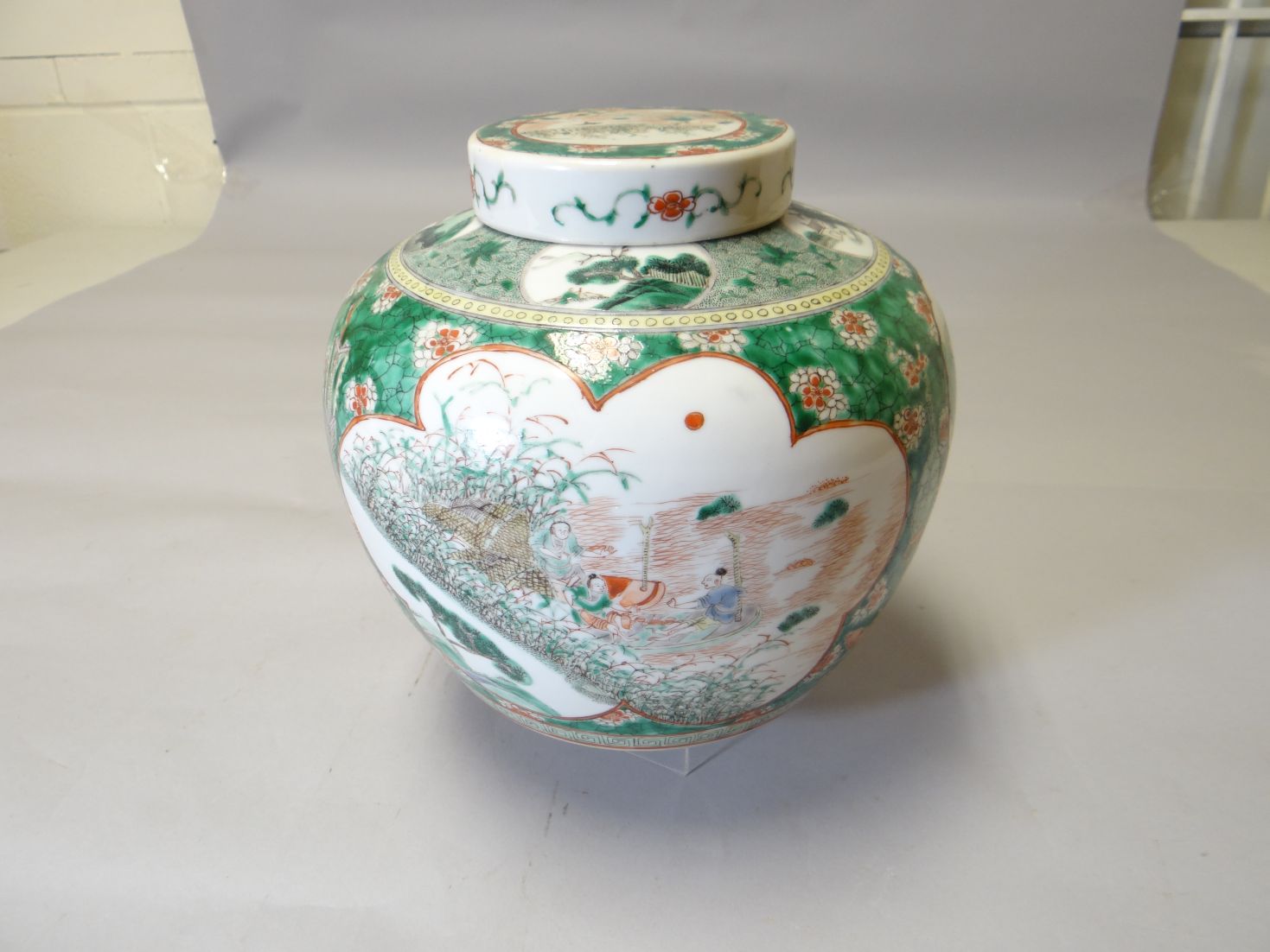 An early twentieth century Famille Vert lidded, bulbous ginger jar profusely decorated with panels