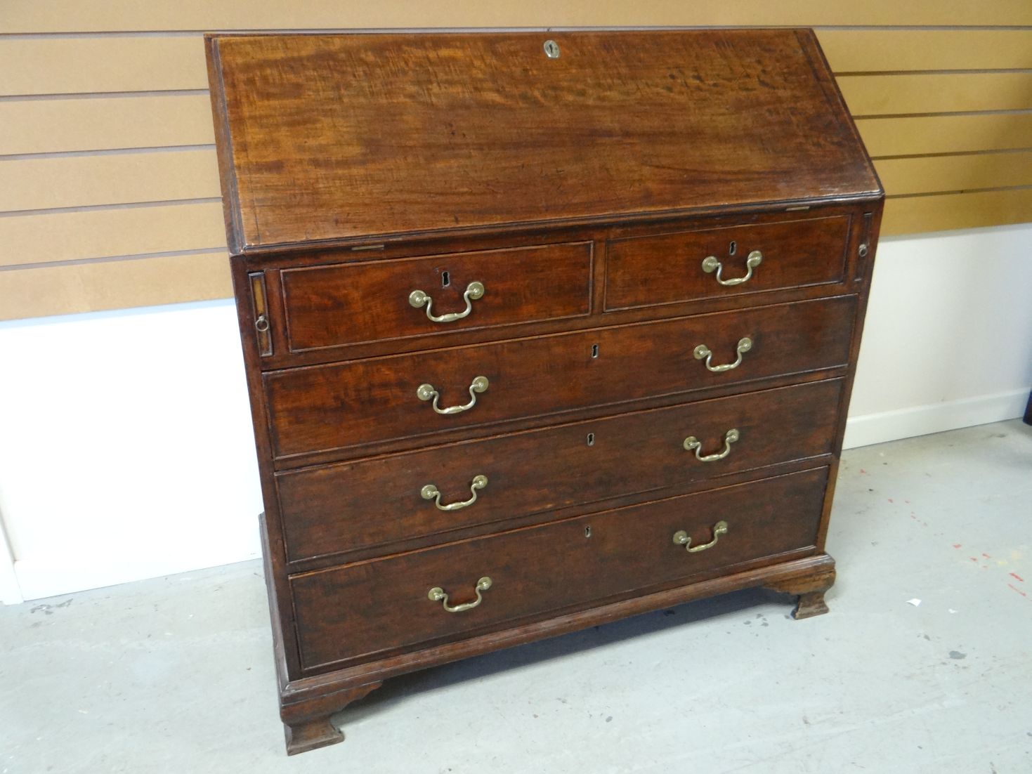 A Georgian mahogany fall-front bureau, of three long and two short drawers, the slope revealing an