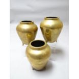 A Chinese trio of matching polished bronze vessels on three feet and each having a large elaborate