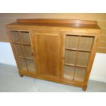 A light oak Brynmawr Furniture 'Gower Dwarf' rail-back triple bookcase having a pair of segmented