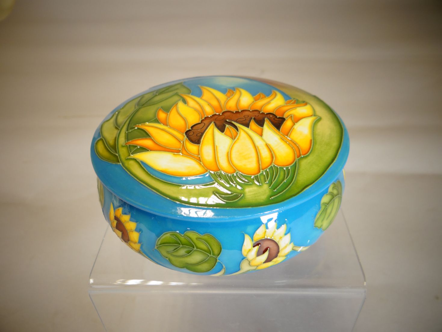 A Moorcroft circular based lidded trinket box in the 'Sunflower' pattern, 5 ins diameter (13 cms)