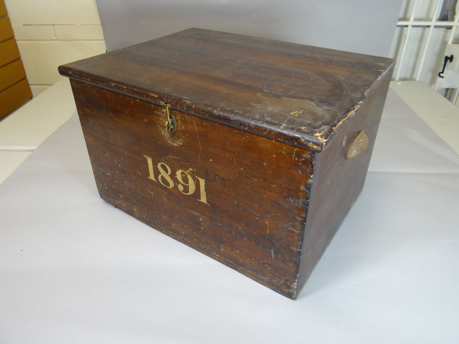 A stained pine deed-box with twin-carry-handles and painted date '1891', 23 ins wide (59 cms)