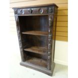 An early twentieth century stained open bookcase profusely carved with lunettes, rosettes and masks,