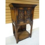 A dark wood Gothic- style raised cupboard with fall-front single door above a lower tier. 51 ins